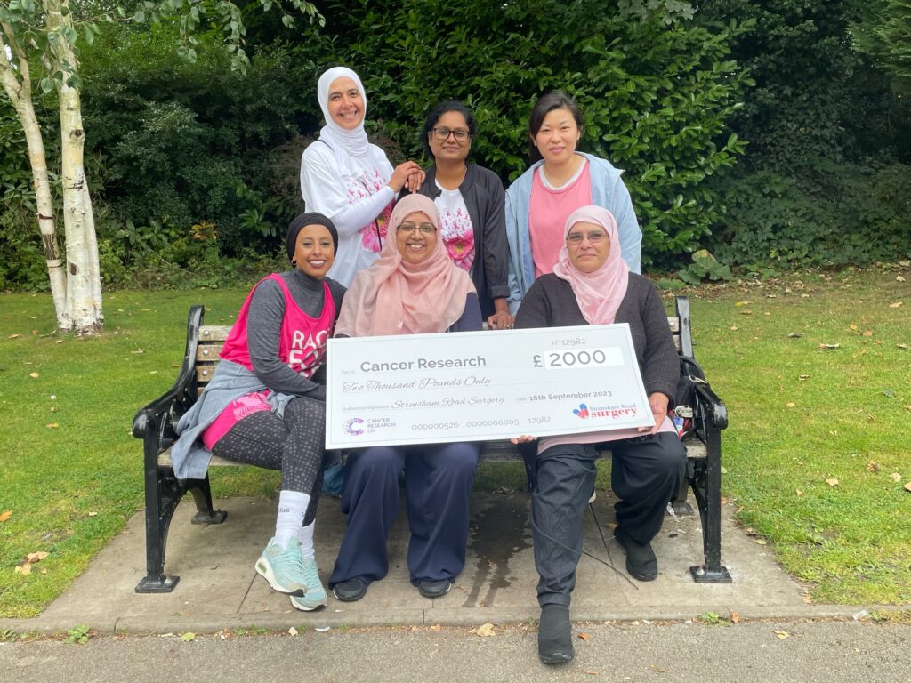 strensham road surgery staff members group photo with a cheque for cancer charity